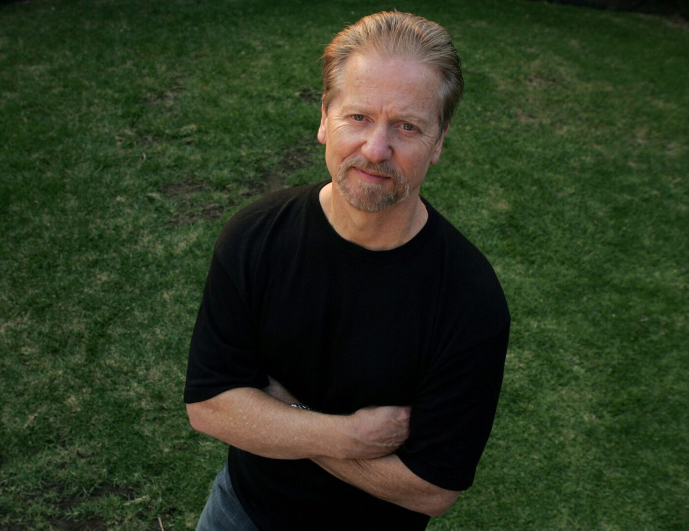 A man standing in the grass with his arms crossed.